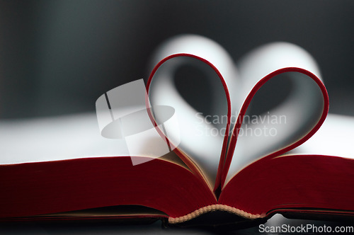 Image of Book, pages and fold with heart shape in closeup for reading, learning or literature by blurred background. Paper, icon and love story with emoji for education, knowledge and development at library