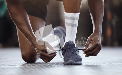 Image of Tie, fitness and hands on shoes at gym for workout, training or exercise or runner ready to start exercising. Black man, goals and tie running shoes in sports performance, health practice or class