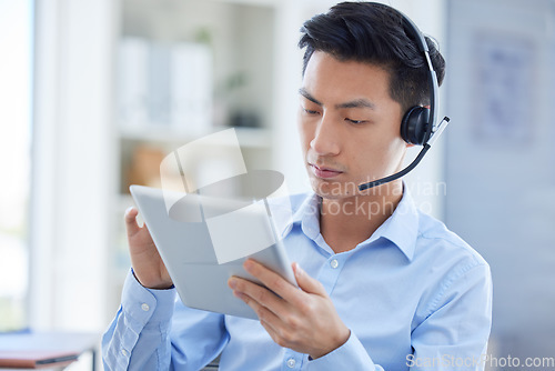 Image of Call center, tablet and focus with asian man in office for consulting, customer service and contact us. Communication, focus and help desk with male employee for technology, digital and networking