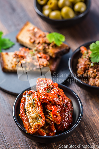 Image of Sun dried tomatoes in olive oil and crostini with tapenade and ingredients. 