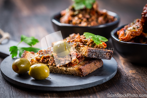 Image of Crispy crostini with tapenade and ingredients. Tapenade - delicious olive paste, French cuisine