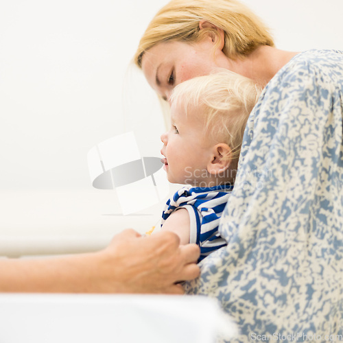 Image of Child beeing vaccinated by pediatrician in presence of his mother. Preventive vaccination against Diphtheria, whooping cough, tetanus, hepatitis, haemophilus influenzae, pneumococcus, poliomyelitis