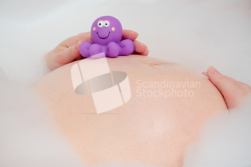 Image of Pregnant woman in bath with toy