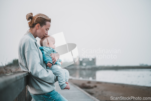 Image of Tender woman caressing her little baby boy infant child outdoors on autumn trip to Secovlje salinas landscape park, Slovenia. Mother's unconditional love for her child.