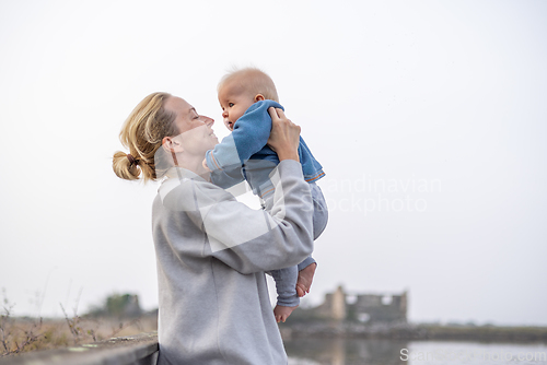 Image of Tender woman caressing her little baby boy infant child outdoors on autumn trip to Secovlje salinas landscape park, Slovenia. Mother's unconditional love for her child.