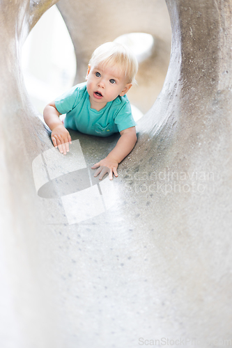 Image of Child playing on outdoor playground. Toddler plays on school or kindergarten yard. Active kid on stone sculpured slide. Healthy summer activity for children. Little boy climbing outdoors.