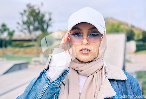 Image of Portrait, fashion or sunglasses with an islamic woman outdoor in a cap and scarf for contemporary style. Muslim, faith or hijab with a trendy young arab female person posing outside in modern eyewear