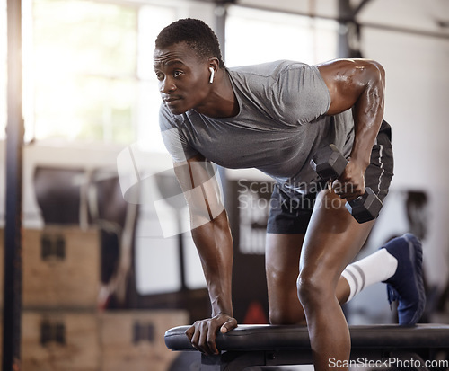 Image of Dumbbells, bench and exercise with a black man at gym for fitness, training workout and strong muscle. African bodybuilder person with weights for power, focus or performance with earphones for music