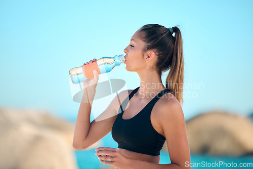 Image of Beach, exercise and woman drinking water, health and training with stress relief, relax and break. Female person, girl and athlete outdoor, liquid and workout goal with hydration, fitness or wellness