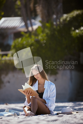 Image of Woman on the beach, reading book and travel, relax in nature in summer holiday with peace and calm. Young female person is outdoor with novel to read, seaside vacation and relaxation in the sun