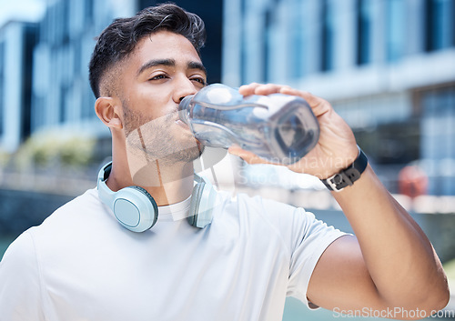 Image of Man, fitness and drinking water in city after exercise, cardio workout or training outdoors. Thirsty male person, athlete or runner with drink for hydration, rest or break from run in an urban town