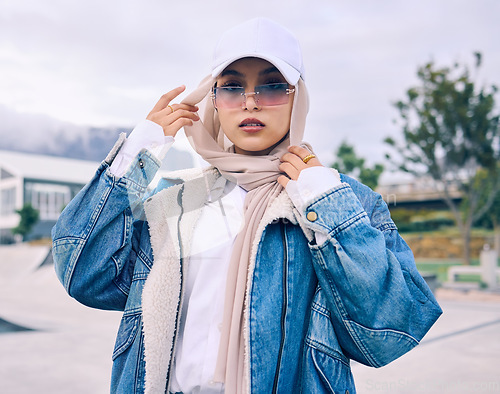 Image of Portrait, sunglasses or religion with a muslim woman outdoor in a cap and scarf for contemporary style. Islam, fashion or hijab with a trendy young arab female person posing outside in modern clothes