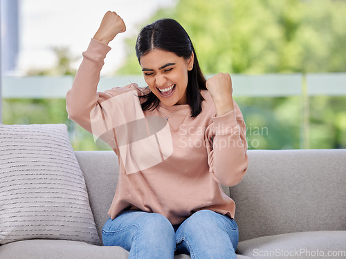 Image of Woman, sofa and fist celebration in home living room, excited and winning with goals, motivation or prize. Girl, winner and happiness for success, celebrate and achievement on lounge couch in house