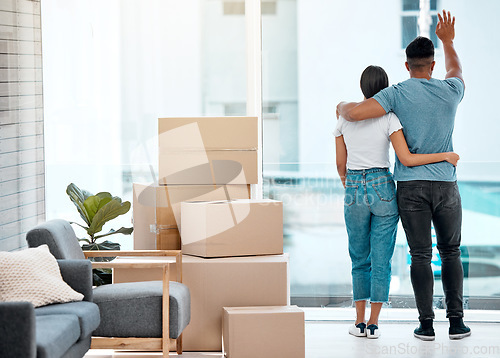 Image of Box, hug and back of couple in new home for property, apartment and real estate investment. Relationship, house and man and woman wave hello to neighbour, embrace and boxes for moving day by a window