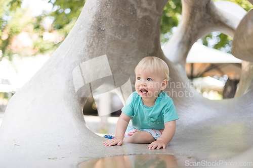 Image of Child playing on outdoor playground. Toddler plays on school or kindergarten yard. Active kid on stone sculpured slide. Healthy summer activity for children. Little boy climbing outdoors.