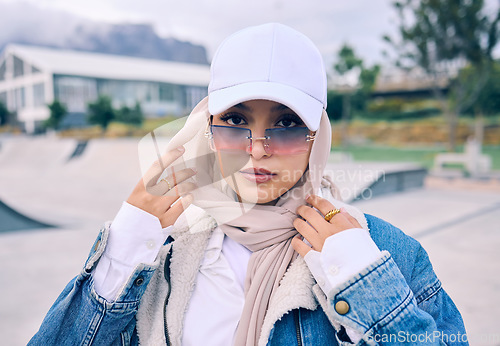 Image of Portrait, fashion or sunglasses with an islam woman outdoor in a cap and scarf for contemporary style. Arab, face and hijab with a trendy young muslim female person posing outside in modern eyewear