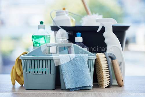 Image of Basket, table and product for cleaning home with brush, cloth and chemical for hygiene by blurred background. Empty house, desk and plastic container for services, stop bacteria and dust in interior