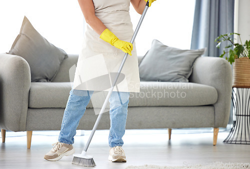 Image of Cleaning, broom and sweeping with a housekeeper in the living room of a home for housework or chores. Floor, sweep and housekeeping with a cleaner in a house to tidy for hygiene during a spring clean