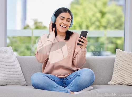 Image of Woman, headphones and phone for singing on sofa for happiness, relax and sound in home living room. Girl, smartphone and audio streaming subscription for hip hop, rock or edm on lounge couch in house