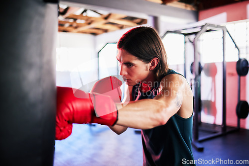 Image of Punching bag, man and boxing in gym for exercise, workout or training for fight. Boxer, sports and serious fitness athlete punch for challenge, competition or exercising body for martial arts power.