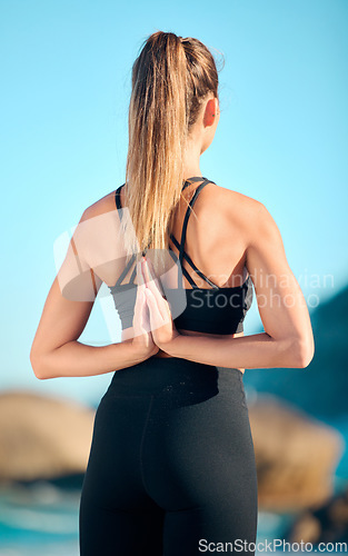 Image of Woman, beach yoga and namaste behind back for fitness, wellness or exercise with peace, nature or freedom. Girl, pilates workout and ocean for mindfulness, muscle or chakra balance in summer sunshine
