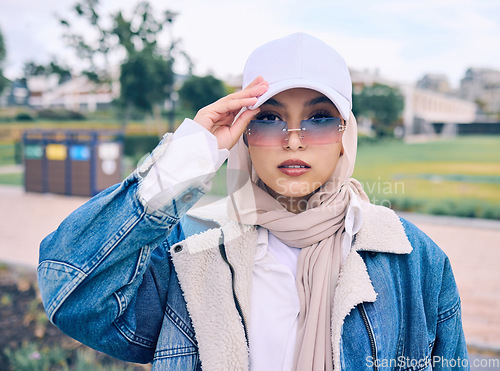 Image of Portrait, fashion or eyewear with a muslim woman outdoor in a cap and scarf for contemporary style. Islam, faith and hijab with a trendy young arab female person posing outside in modern sunglasses