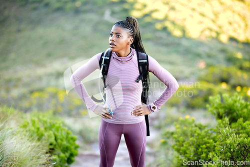 Image of Black woman, hiking and thinking outdoor in nature with a backpack for adventure, fitness and breathing. Tired african person with hands on hips for break from mountain climbing, exercise or trekking