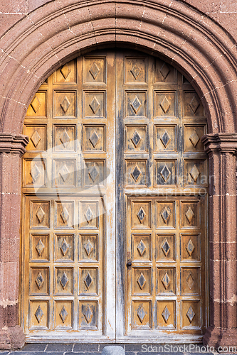 Image of Big beautiful ornate wooden door, framed by a decorated stone arch. Entrance to iglesia de nuestra senora de guadalupe, Teguise, Lanzarote, Canary Islands, Spain.