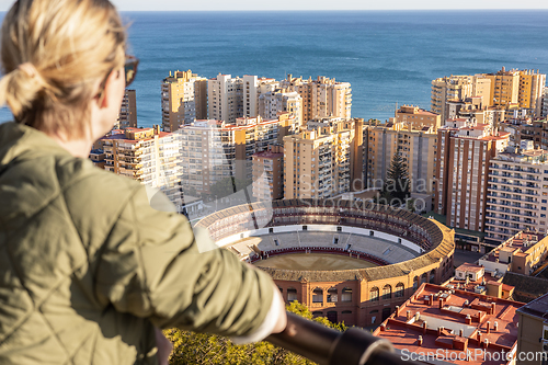 Image of Bolnde female touris enjoying amazing panoramic aerial view of bull ring in Malaga, Spain