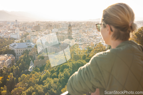 Image of Bolnde female touris enjoying amazing panoramic aerial view of Malaga city historic center, Coste del Sol, Andalucia, Spain.