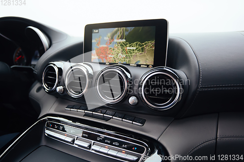 Image of View from inside a car on a part of dashboard with a navigation unit and blurred street in front of a car