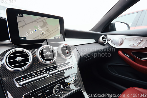 Image of View from inside a car on a part of dashboard with a navigation unit and blurred street in front of a car