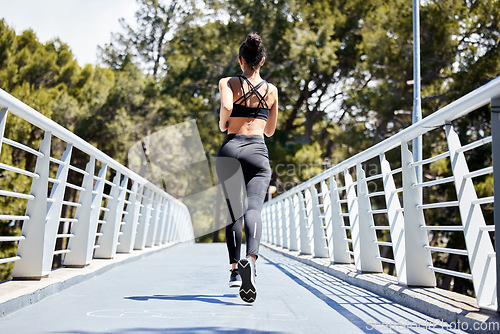 Image of Woman, fitness and running on bridge for exercise, cardio workout or training in nature outdoors. Rear view of fit, active and sports female person, athlete or runner exercising for healthy wellness