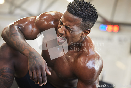 Image of Exercise, muscle and pain with a black man bodybuilder breathing in the gym, exhausted after a workout. Fitness, injury and sweat with a intense, shirtless male athlete taking a break from training