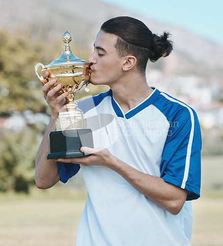 Image of Soccer player, celebrate and competition with trophy in the outdoor with a kiss after win. Sports person, champion and football with award on a field with happiness for winning a game as achievement.