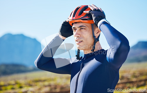 Image of Mountain, helmet and man cycling in a marathon, fitness training or competition or sports adventure with blue sky. Gear, athlete and safety in outdoor cycle, bike ride or exercise in nature or park