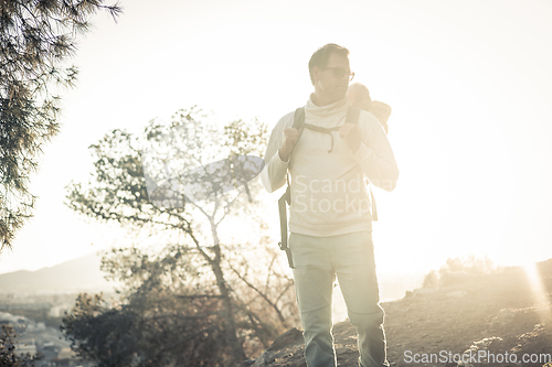 Image of Young father carrying his infant baby boy son in backpack while tracking around Malaga, Spain in sunset. Family travel and vacation concept