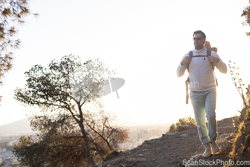 Image of Young father carrying his infant baby boy son in backpack while tracking around Malaga, Spain in sunset. Family travel and vacation concept