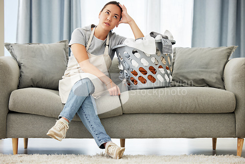 Image of Home, thinking and Asian woman on a couch, laundry basket and tired with chores, cleaning or bored. Female person, cleaner or maid on sofa, hygiene or exhausted with housekeeping, thoughts or fatigue