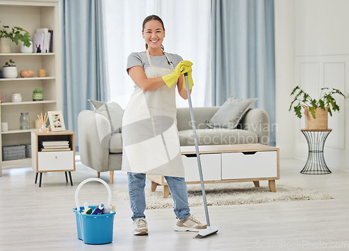 Image of Portrait, broom and a woman cleaner sweeping the living room of a home for hygiene, service or housework. Smile, spring cleaning or housekeeping with an asian female maid standing in a domestic house