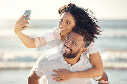 Image of Couple, piggyback and selfie at beach, smile and happy on holiday with summer sunshine for blog, post and web. Man, woman and photography for romantic vacation, profile picture and social media app