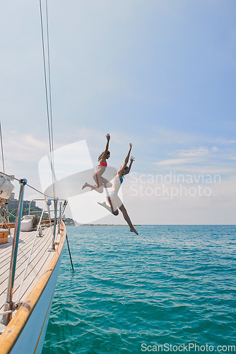 Image of Summer, sailing and friends jumping off a yacht together into the ocean for freedom, fun or swimming. Travel, energy and bikini with girls leaving a boat to jump into the sea while on a luxury cruise