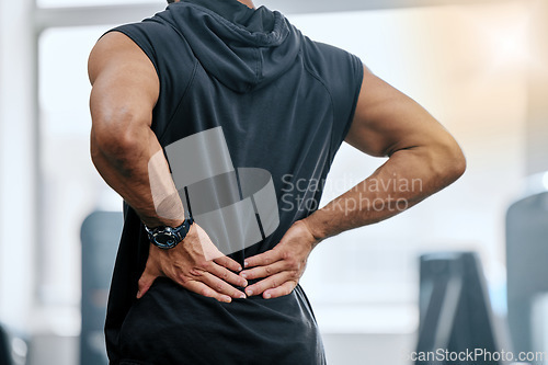 Image of Gym, injury and man with hand on back pain for medical emergency from workout at sports studio. Exercise, health and wellness, bodybuilder with hands on muscle to massage ache or cramp while training