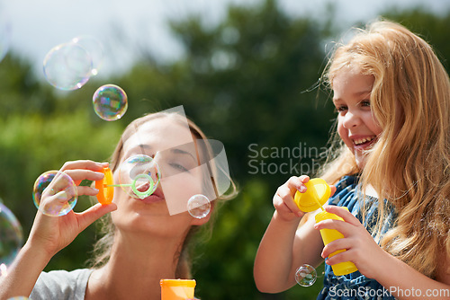 Image of Mother blowing bubbles with daughter, happiness outdoor with bonding and love with childhood and parenting. Woman playing outside with young girl, mom and female child with fun activity together