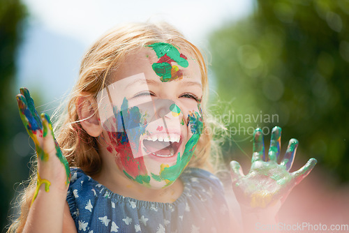 Image of Happy, little girl covered in paint and outdoors with a lens flare. Happiness or creative, playing or art fun and cheerful or excited young child with painting over her face outside in the summer