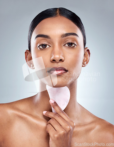 Image of Beauty, skincare and gua sha with portrait of woman in studio for massage, wellness or cosmetics. Spa, self care and glow with model on grey background for facial, cosmetology and rose quartz crystal