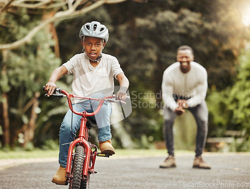 Image of Boy on bicycle, father cheers and learning cycling with help, helmet for safety and family in park. Support, motivation and trust, black man and young kid outdoor, teaching and learn bike riding