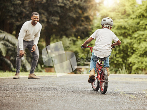 Image of Boy on bicycle, father cheers and learn cycling with help, helmet for safety and family in park. Support, motivation and trust, black man and young kid outdoor, teaching and learning bike riding