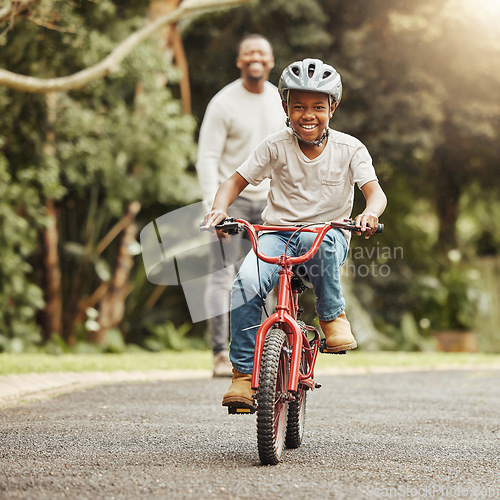 Image of Boy with smile on bicycle, father and learn cycling with help, helmet for safety and family in park. Support, motivation and trust, black man and young kid outdoor, teaching and learning bike riding