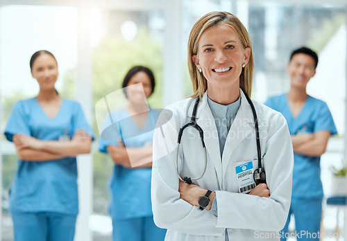 Image of Portrait, team and a doctor woman arms crossed, standing in the hospital for healthcare or medicine. Leadership, medical or teamwork with a mature female health professional in a clinic for treatment